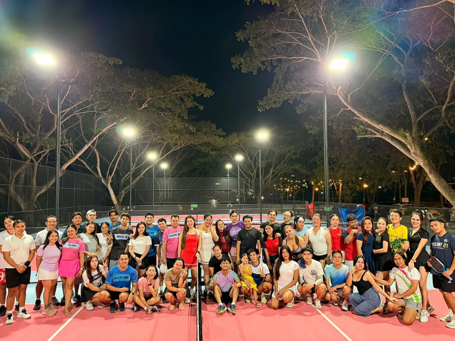 A group of players posing together on the court at night